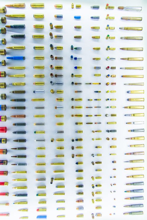 Overhead view of various bullet casings arranged on white surface
